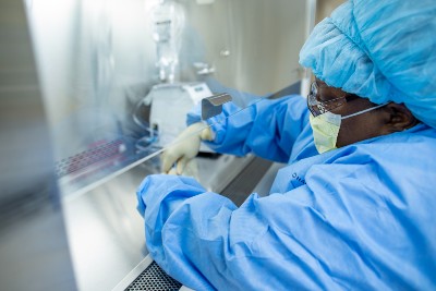 Person in full personal protection equipment including mask and gloves working carefully with pharmaceuticals